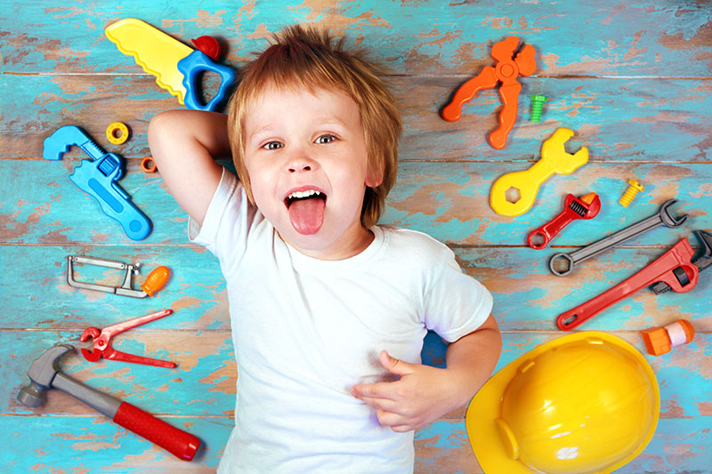 Little boy wearing a white t-shirt, surrounded by toy tools that signify coping skills