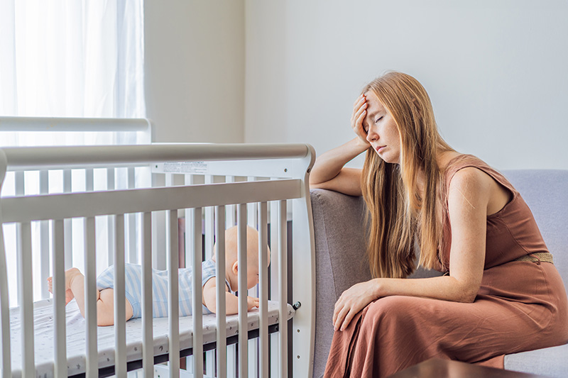 Very Tired Mother Sitting By Baby